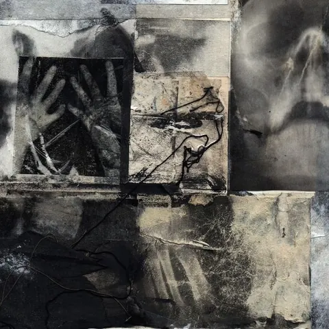 Dark mixed-media surface of charcoal, spray and paper with faint hands and faces emerging.