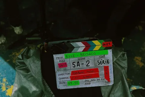 Film clapperboard for a production called "Elle - Beijaço", scene 5A-2, resting on a jacket at night.