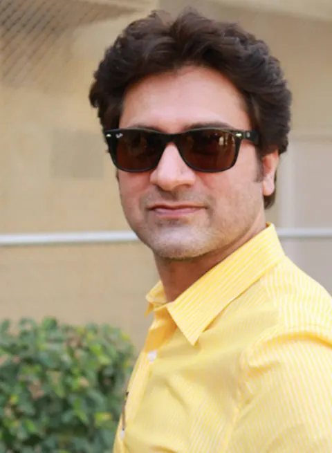 Portrait of Prof. Dr. Jamshed Butt in sunglasses and a yellow shirt, outdoors.