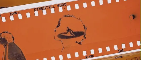 Orange CineStill 400D film strip frame with a hand-drawn profile and landscape.