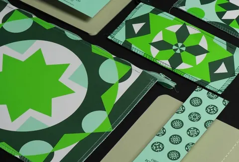Folded fabric/paper printed with bold green geometric star and tile patterns.