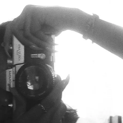 Black-and-white close-up of hands holding a vintage rangefinder camera.