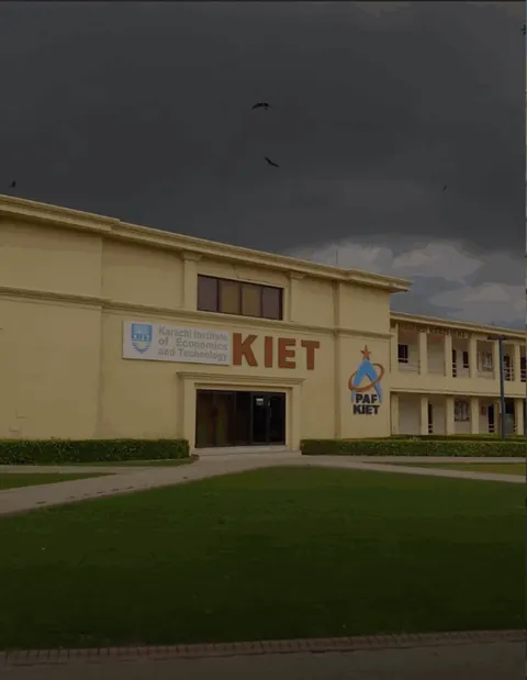 KIET campus front with KIET and PAF-KIET signage, lawn in front, dark sky.