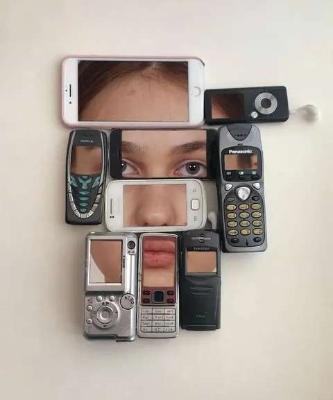 Old mobile phones arranged into a face, each screen showing a fragment of eyes, nose or mouth.