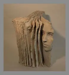 Sculpture of a face emerging from layered, torn paper sheets.