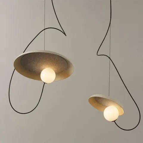 Two sculptural pendant lamps with shallow dishes and glowing globes on long looping black cords.