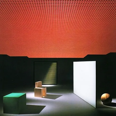 Minimal dark room with a glowing red grid ceiling, a green cube, wooden chair, white door panel and a sphere.
