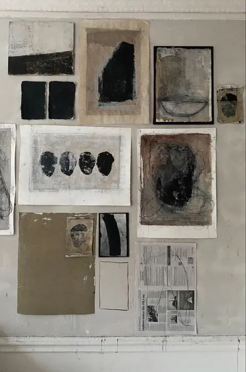 Artist studio wall pinned with abstract ink, charcoal and paper works.