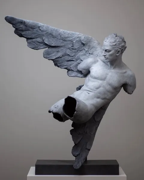 Grey sculpture of a winged male torso, fragmented and broken, on a plinth.